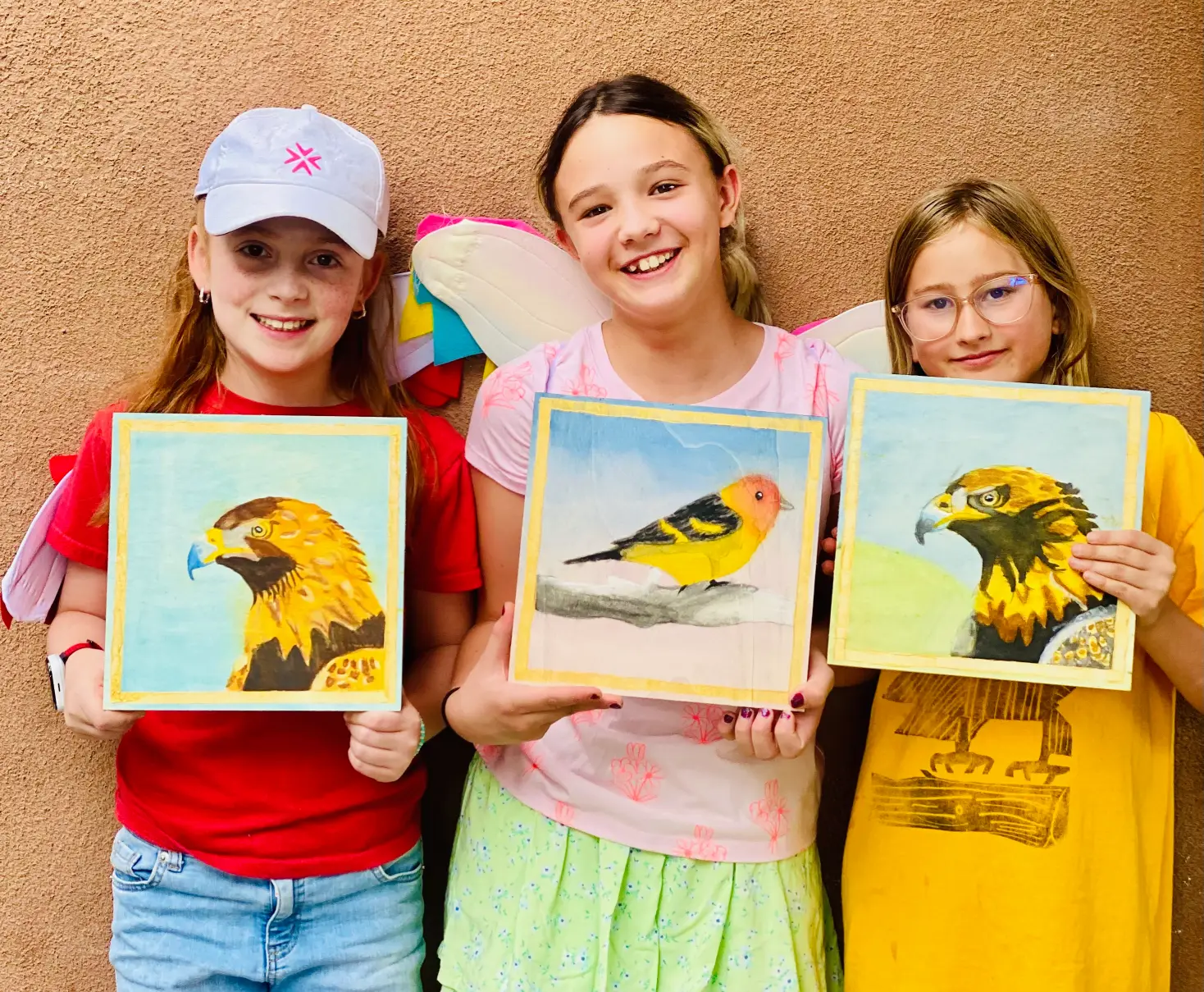three students show off their bird and eagle paintings